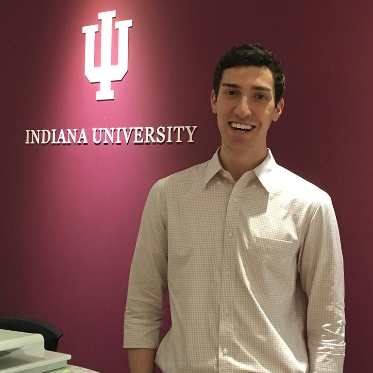 Student standing in front of Indiana University sign